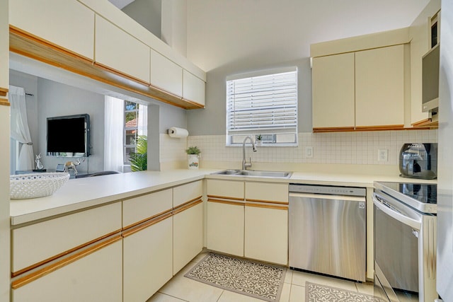 kitchen featuring appliances with stainless steel finishes, sink, cream cabinetry, and decorative backsplash