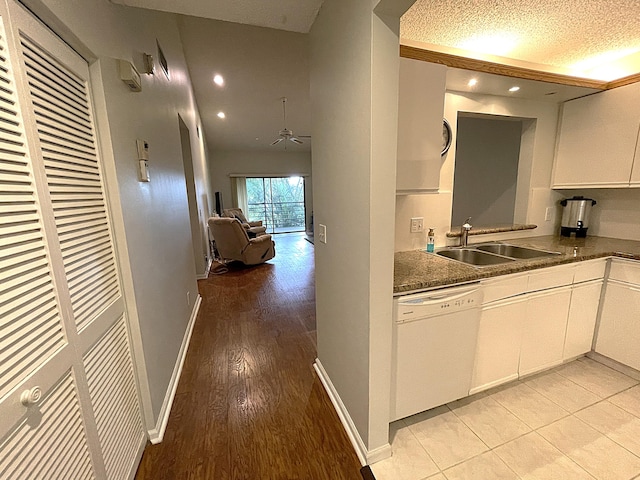 kitchen featuring white dishwasher, sink, white cabinetry, a textured ceiling, and light hardwood / wood-style floors