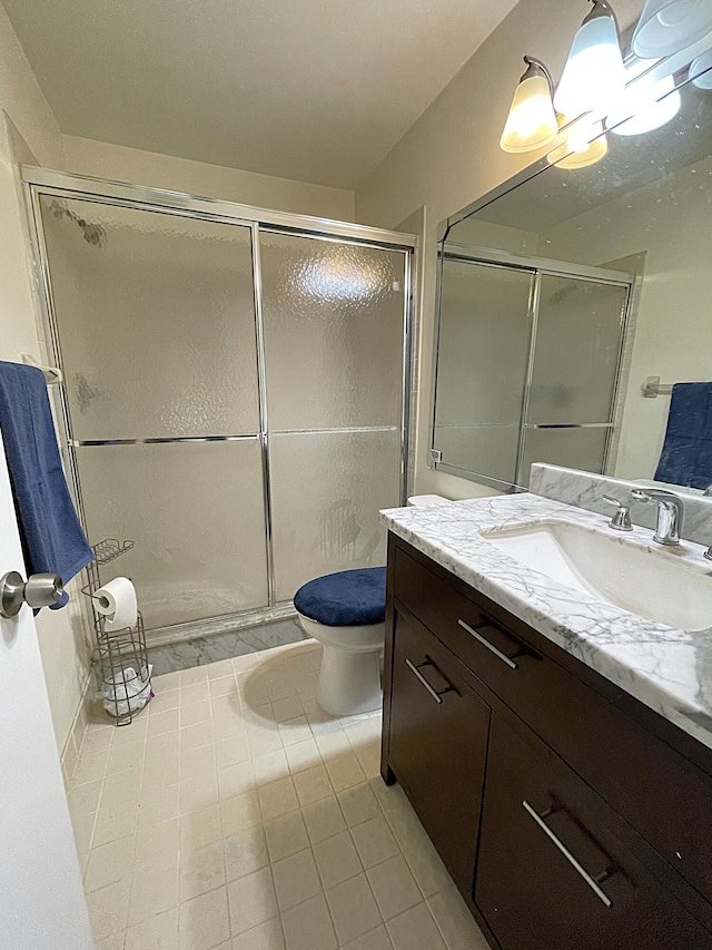 bathroom featuring vanity, tile patterned flooring, toilet, and walk in shower