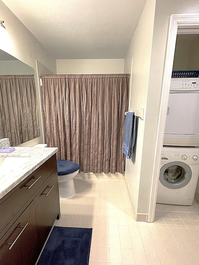 bathroom with vanity, stacked washer and clothes dryer, toilet, and tile patterned flooring