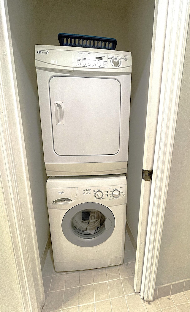 laundry room featuring stacked washer and clothes dryer and light tile patterned floors