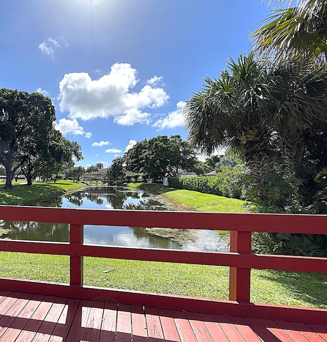 wooden deck with a lawn and a water view