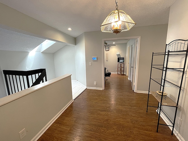 corridor featuring a textured ceiling, dark hardwood / wood-style floors, and an inviting chandelier