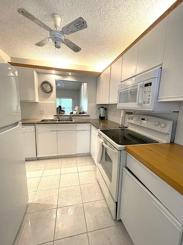 kitchen featuring light tile patterned flooring, white cabinets, a textured ceiling, and white appliances