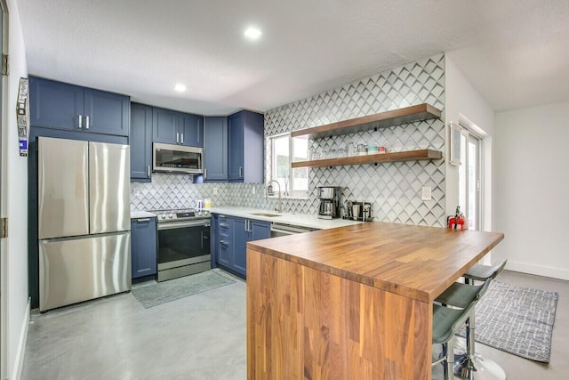 kitchen featuring stainless steel appliances, sink, kitchen peninsula, tasteful backsplash, and blue cabinetry