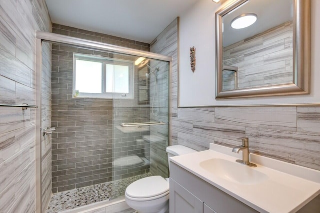 bathroom with toilet, vanity, tile walls, and a shower with door