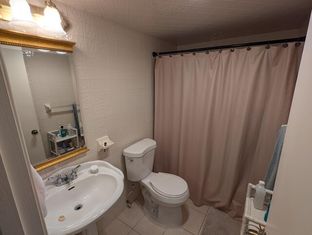 bathroom with tile walls, toilet, sink, a shower with shower curtain, and tile patterned flooring