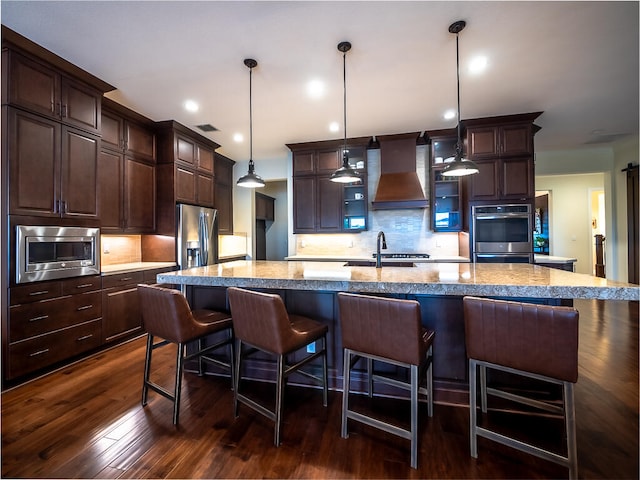 kitchen featuring a spacious island, custom range hood, appliances with stainless steel finishes, and pendant lighting