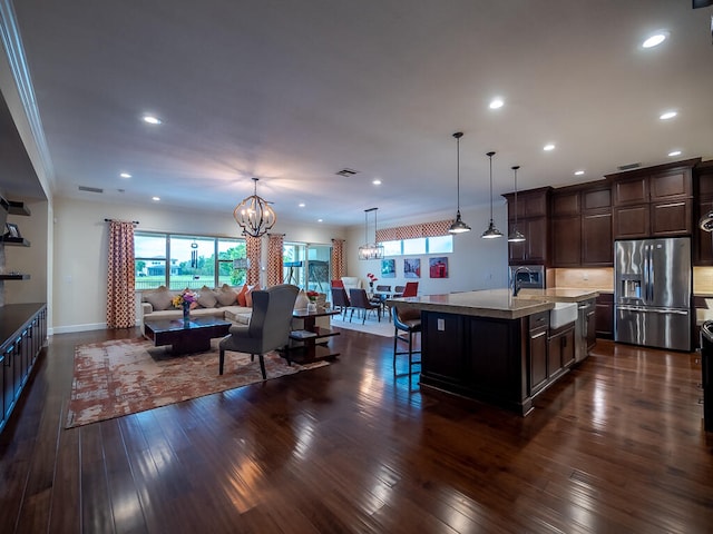 kitchen with stainless steel fridge, a healthy amount of sunlight, sink, and a center island with sink