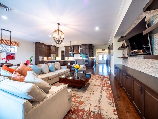 living room with crown molding, a chandelier, sink, and dark hardwood / wood-style flooring