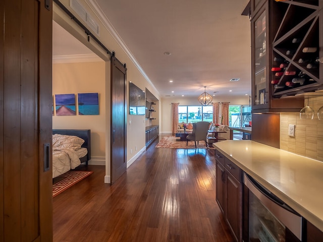 interior space with wine cooler, an inviting chandelier, a barn door, ornamental molding, and dark hardwood / wood-style floors