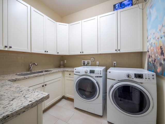 washroom with cabinets, light tile patterned flooring, sink, and washing machine and clothes dryer