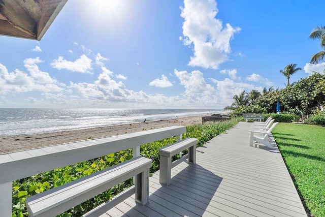 wooden terrace featuring a yard, a water view, and a view of the beach