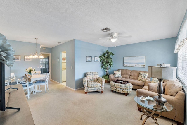 carpeted living room featuring a textured ceiling and ceiling fan with notable chandelier