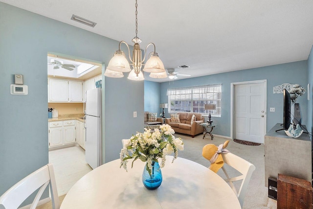 carpeted dining room with a skylight and ceiling fan with notable chandelier