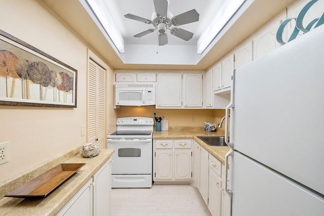 kitchen with light hardwood / wood-style floors, white cabinetry, sink, and white appliances