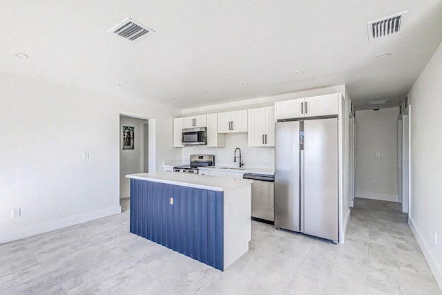 kitchen with appliances with stainless steel finishes, a center island, white cabinetry, and sink