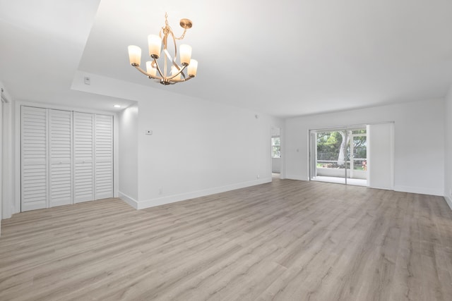 unfurnished living room featuring light hardwood / wood-style floors and a notable chandelier