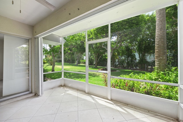 unfurnished sunroom featuring ceiling fan and plenty of natural light