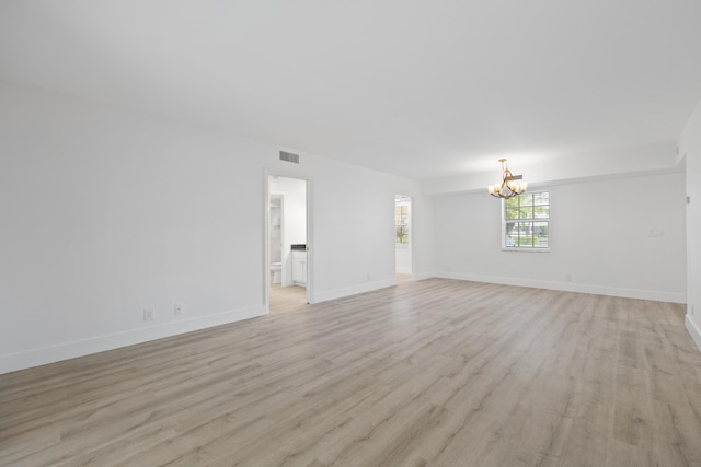 empty room featuring light hardwood / wood-style floors and an inviting chandelier