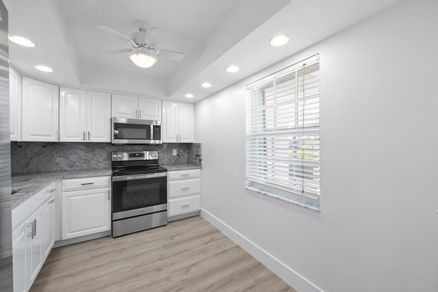 kitchen featuring white cabinets, stainless steel appliances, light hardwood / wood-style floors, and tasteful backsplash