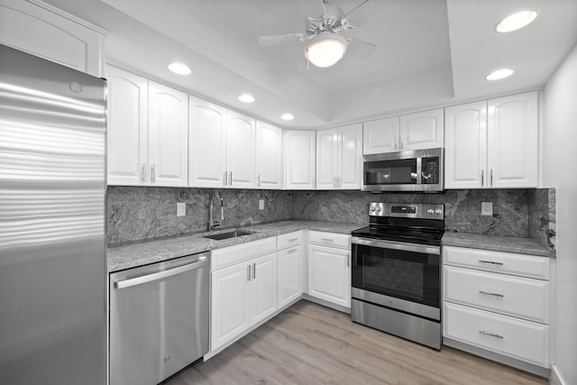 kitchen with sink, white cabinets, stainless steel appliances, and light wood-type flooring