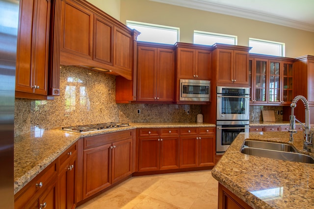 kitchen with appliances with stainless steel finishes, ornamental molding, tasteful backsplash, and sink