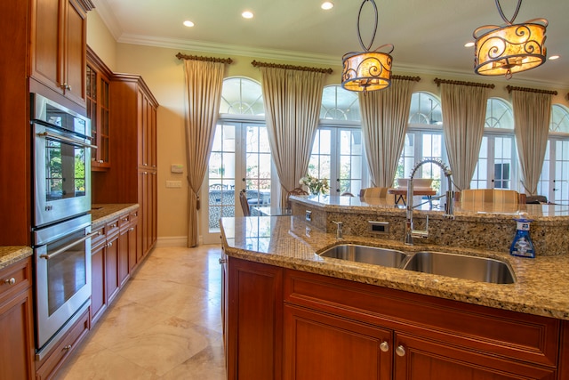 kitchen featuring french doors, stainless steel double oven, pendant lighting, light stone counters, and ornamental molding