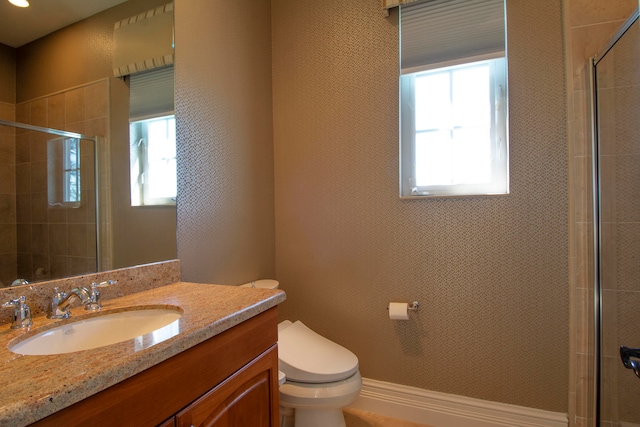 bathroom featuring toilet, an enclosed shower, a healthy amount of sunlight, and vanity