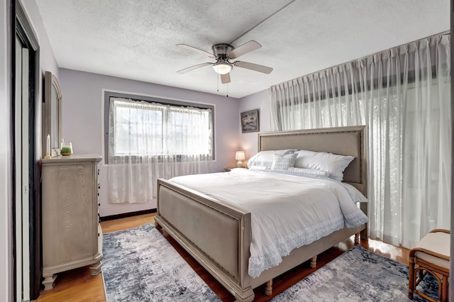 bedroom with a textured ceiling, light wood-type flooring, and ceiling fan