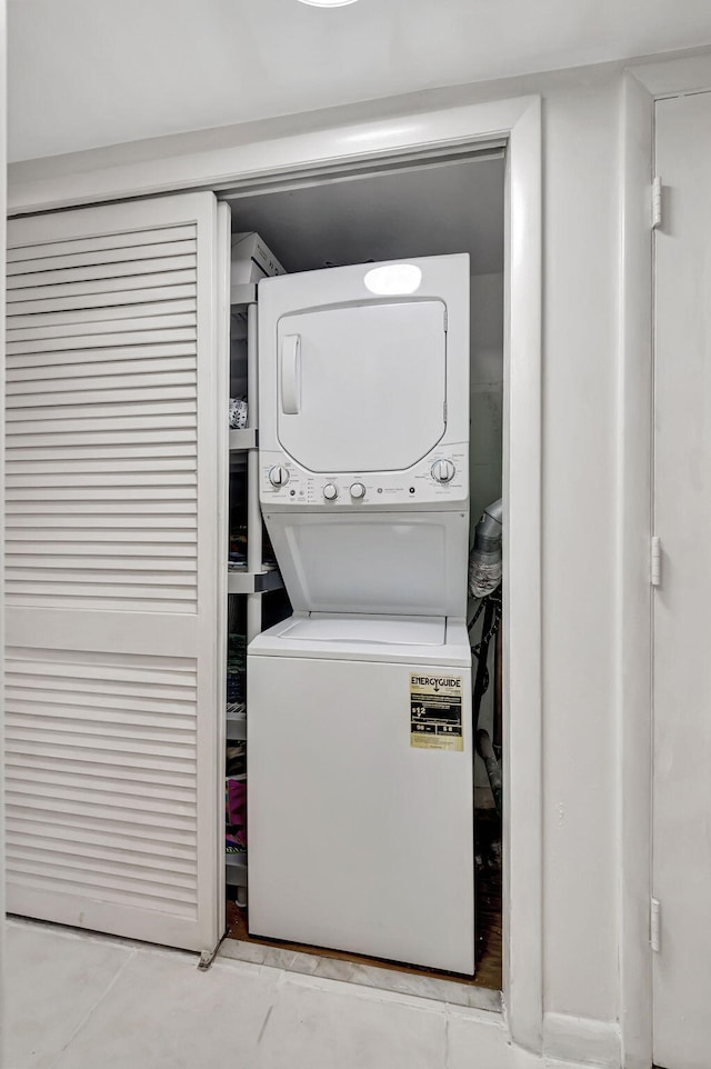 laundry room with stacked washer / dryer and light tile patterned floors