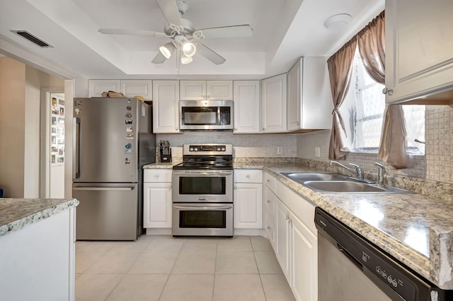 kitchen featuring sink, stainless steel appliances, a tray ceiling, and white cabinets