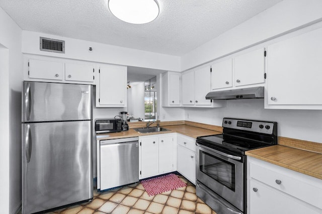 kitchen with sink, appliances with stainless steel finishes, a textured ceiling, and white cabinetry