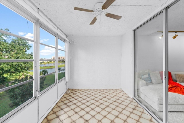 sunroom / solarium with a water view and ceiling fan