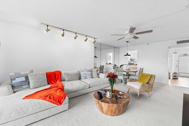 living room featuring a textured ceiling, track lighting, and ceiling fan