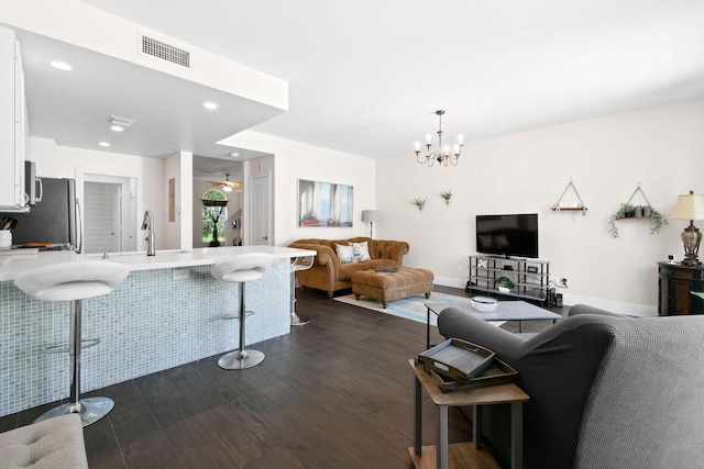 living room featuring dark wood-style flooring, recessed lighting, visible vents, baseboards, and ceiling fan with notable chandelier