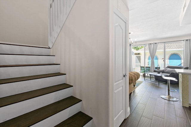 stairs featuring wood tiled floor and a notable chandelier