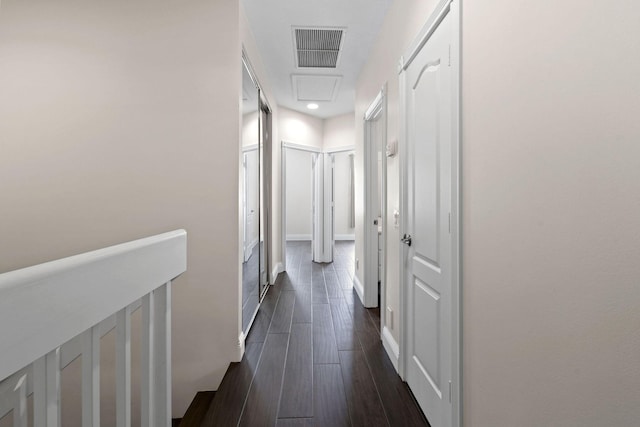 hall featuring attic access, dark wood-style flooring, visible vents, and baseboards