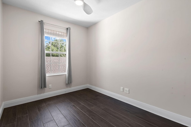 empty room featuring dark wood-type flooring, a ceiling fan, and baseboards