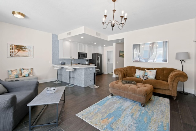 living area featuring dark wood-style flooring, visible vents, baseboards, and an inviting chandelier