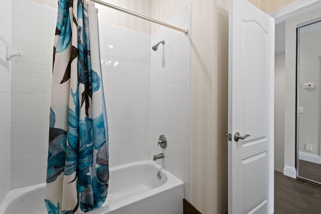 full bathroom with shower / bath combo, wood finished floors, and baseboards