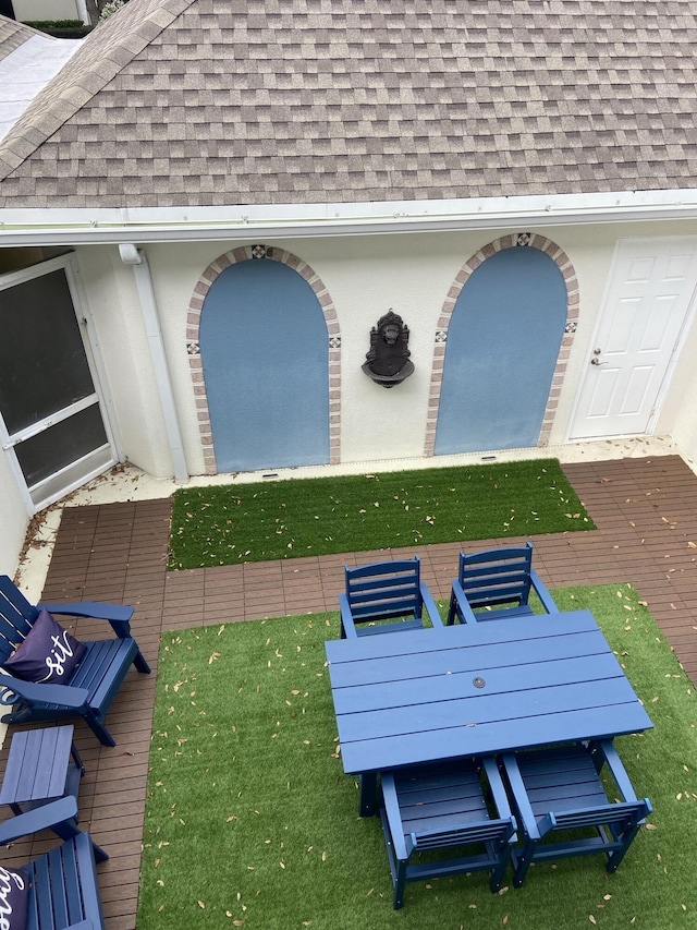 exterior space featuring roof with shingles and stucco siding