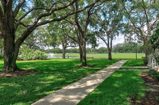 view of property's community with a water view and a lawn