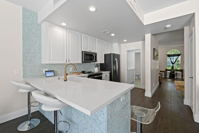 kitchen with stainless steel microwave, a peninsula, fridge with ice dispenser, light countertops, and a kitchen bar