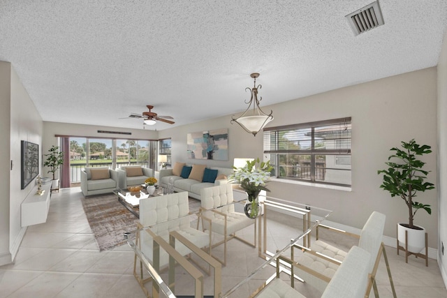 tiled dining room with ceiling fan and a textured ceiling