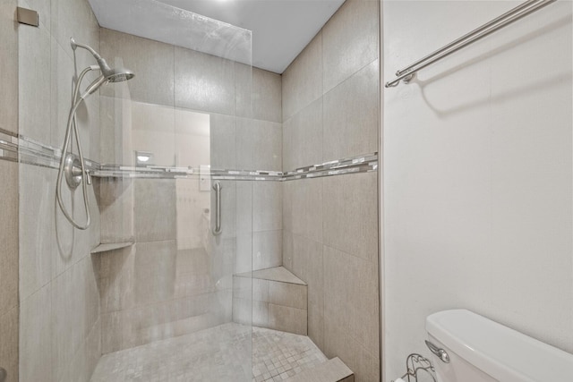 bathroom with a tile shower and toilet