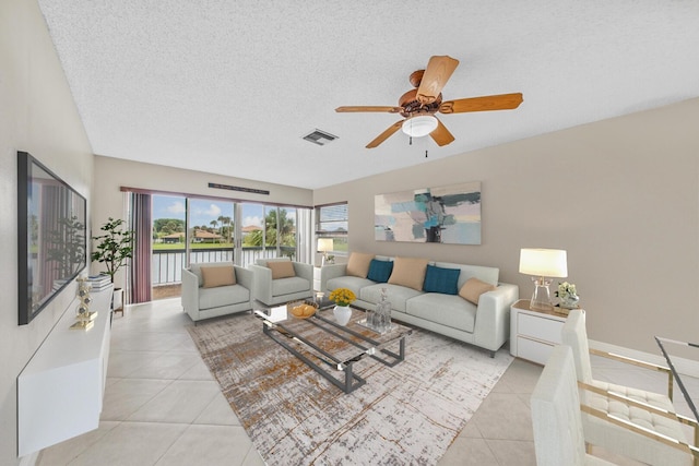 living room featuring ceiling fan, light tile patterned floors, and a textured ceiling