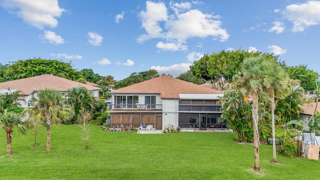 rear view of property with a yard and a balcony