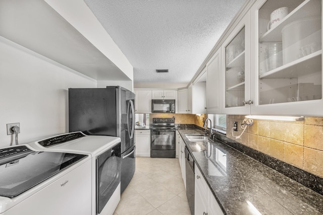 kitchen featuring dark stone counters, black appliances, white cabinets, sink, and separate washer and dryer