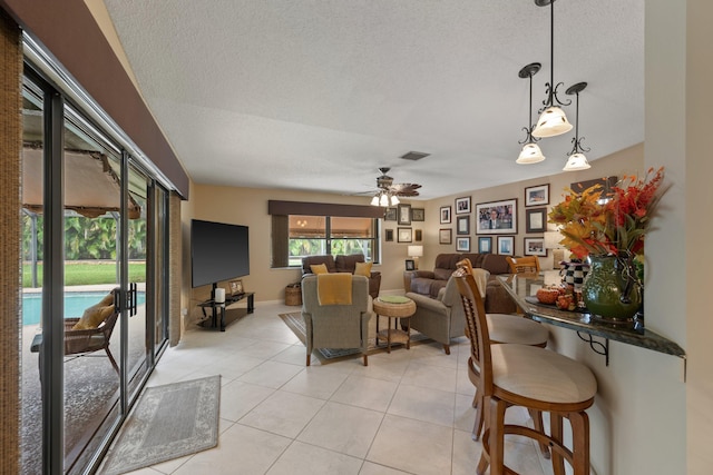 tiled living room with ceiling fan and a textured ceiling